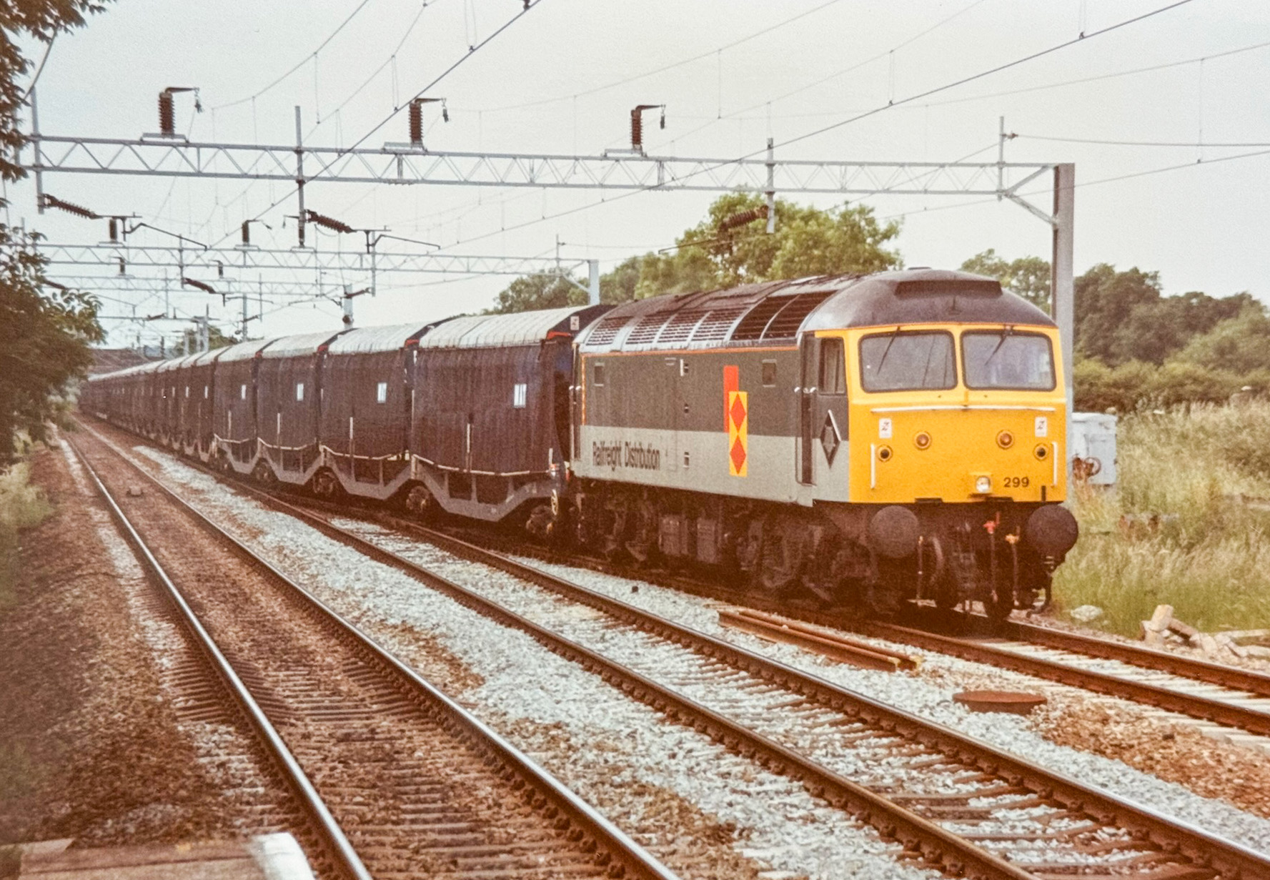 With lengthy MAT set in tow, 47299 with hastily-applied Railfreight Distribution lettering has ample work on June 23, 1994. Though not available with roofs from Revolution Trains, such a project would favour keen 3D-print designers. Howard Smith (TS collection)