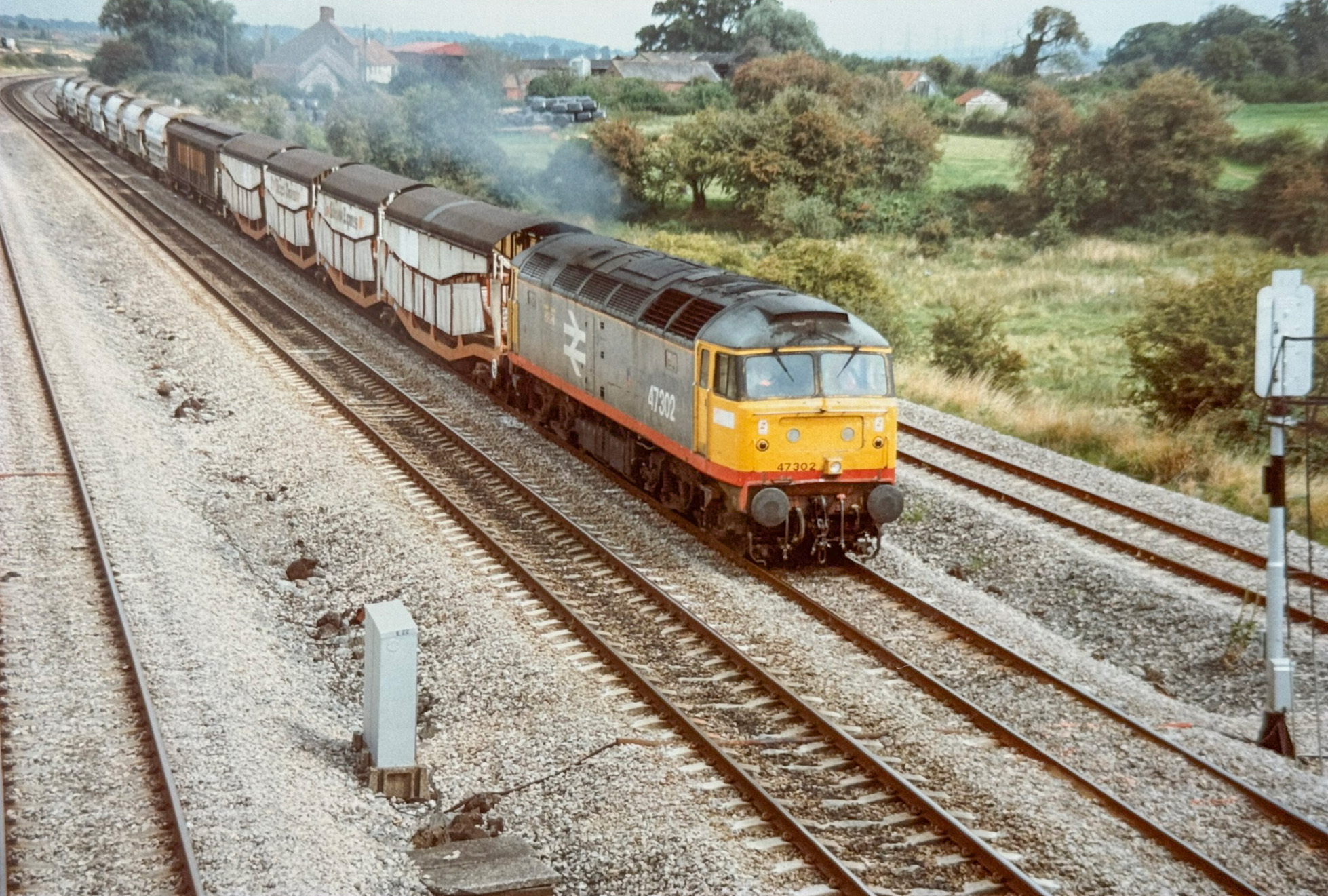 Still carrying Railfreight red stripe livery with large logo, with cab-side vinyl now gone, 47302 'Meridian' with Thornaby depot Kingfisher emblem hauls a 12-wagon rake, led by a Cartic-4 with Silcock Express branding on August 26, 1993. Howard Smith (TS collection)